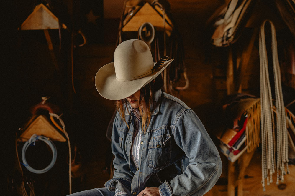 A woman wearing looking down while wearing a cowboy hat.
